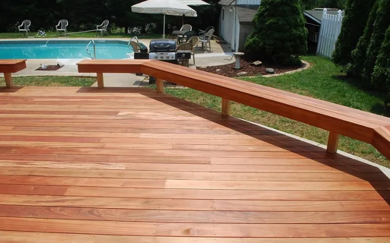 Wooden backyard deck near swimming pool with furniture.